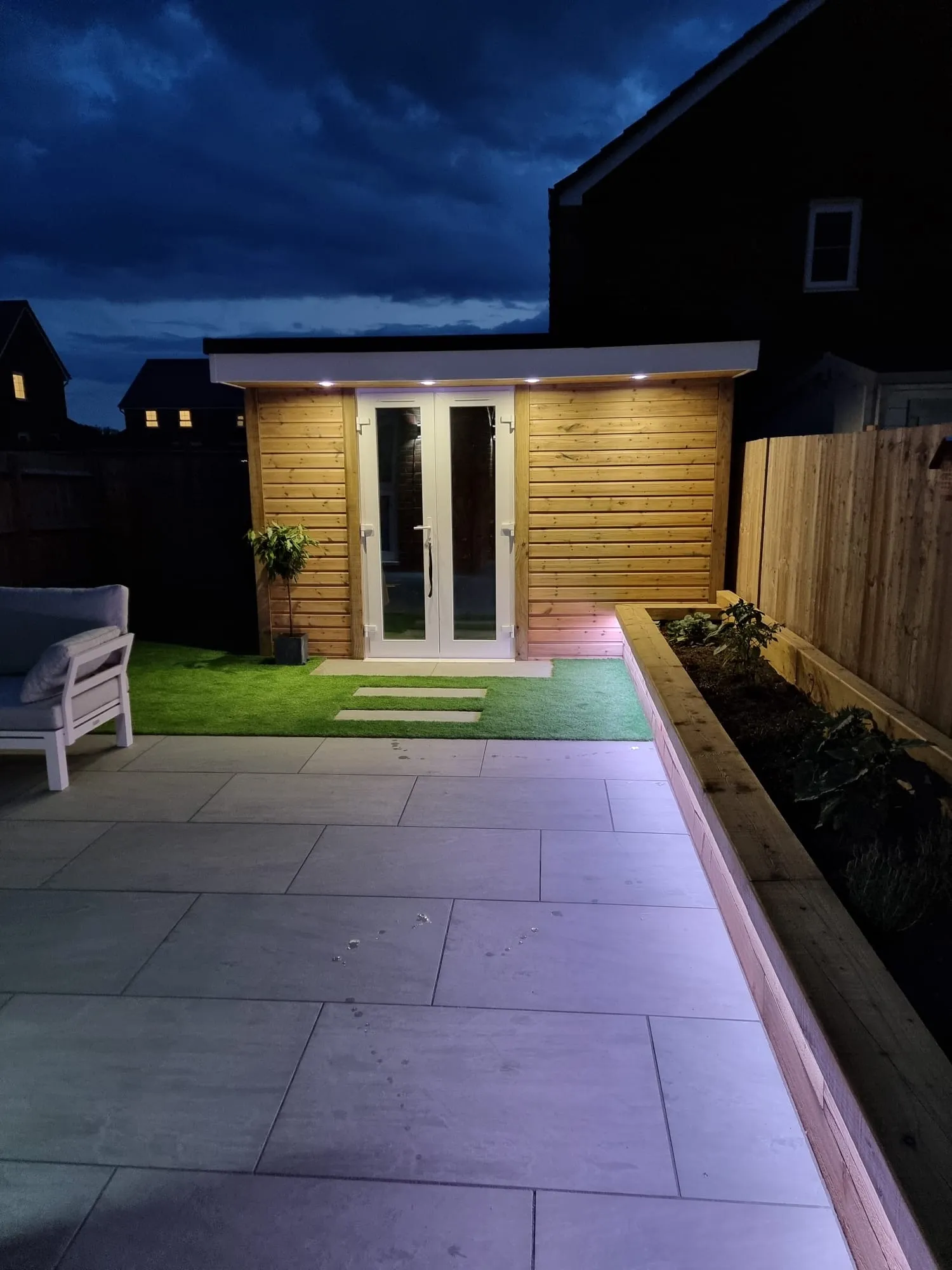 A patio with a bench and a small wooden building.