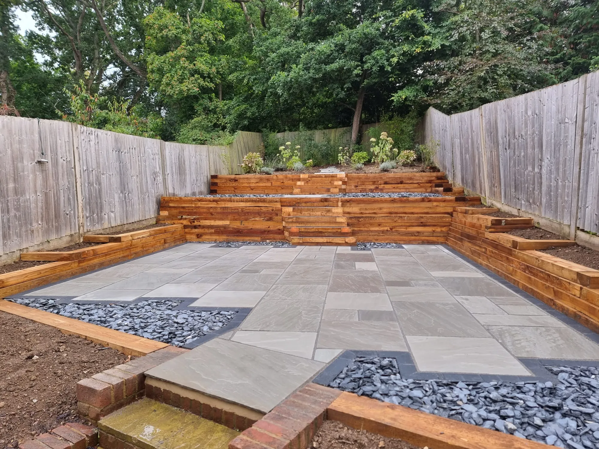 a backyard with a stone patio and wooden steps