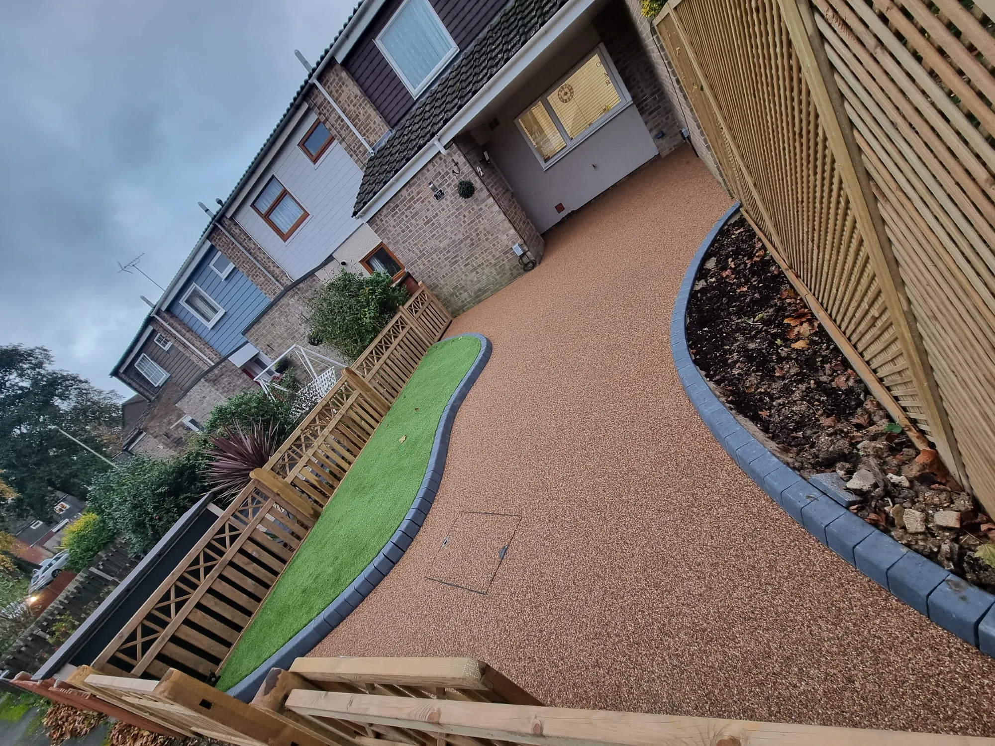 a backyard with a green lawn and a wooden fence
