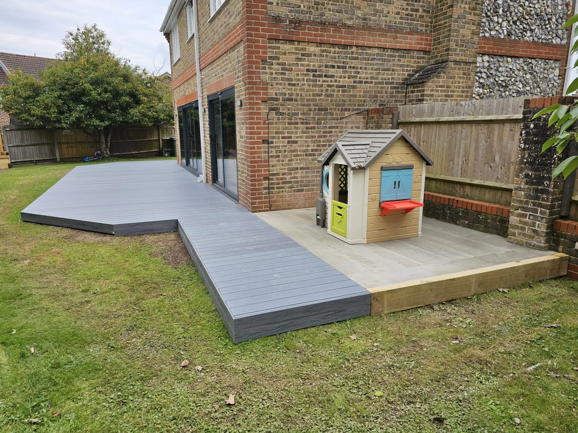a backyard with a play area and a wooden deck