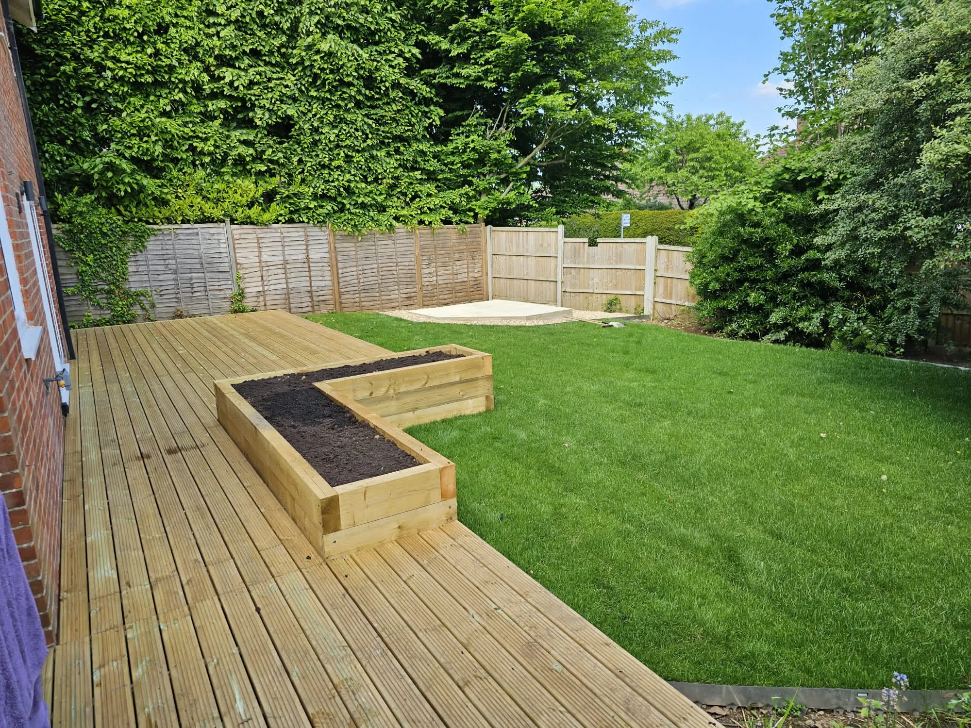 a wooden deck with a raised planter in the middle of it