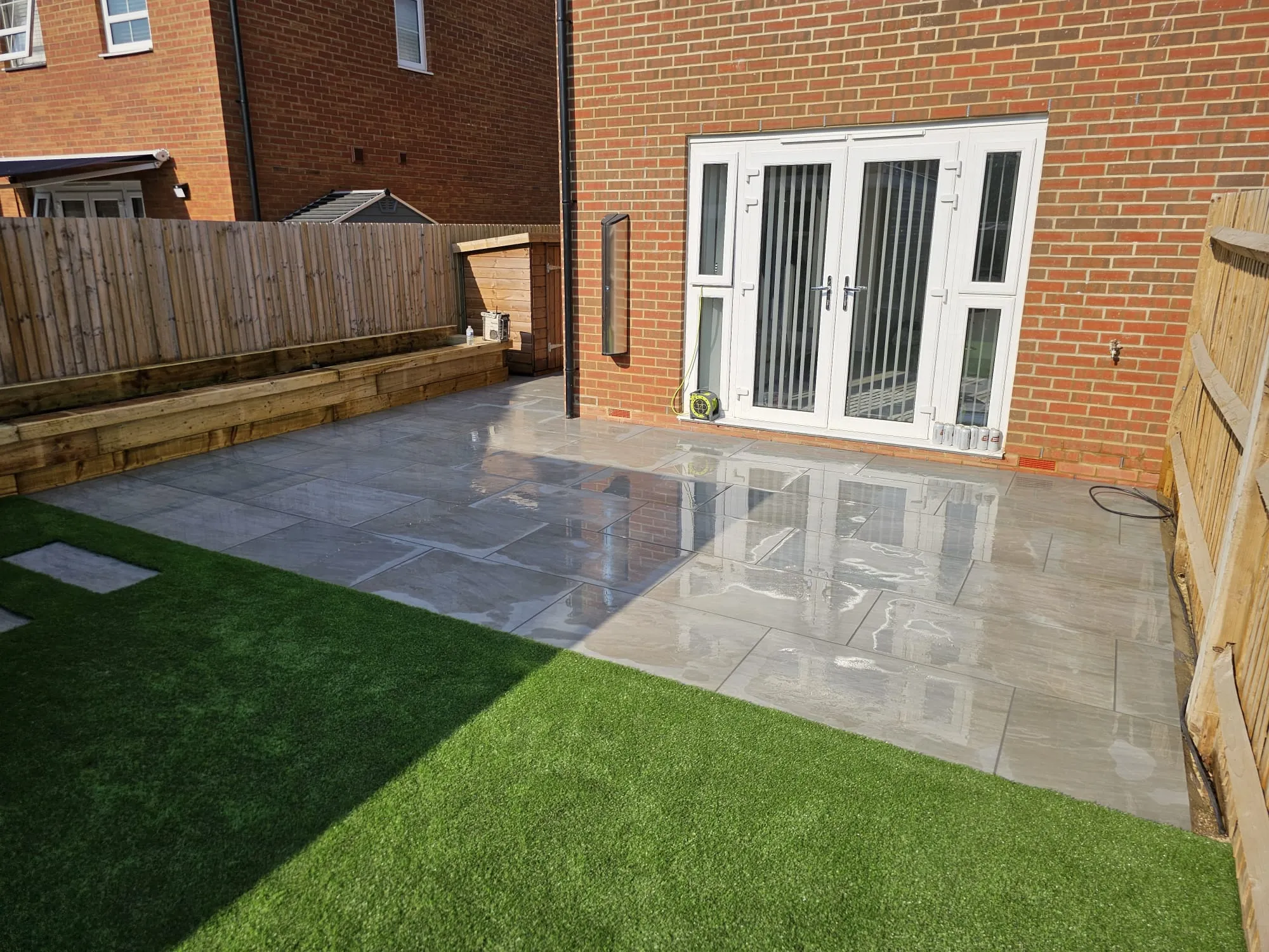 a back yard with artificial grass and a wooden fence
