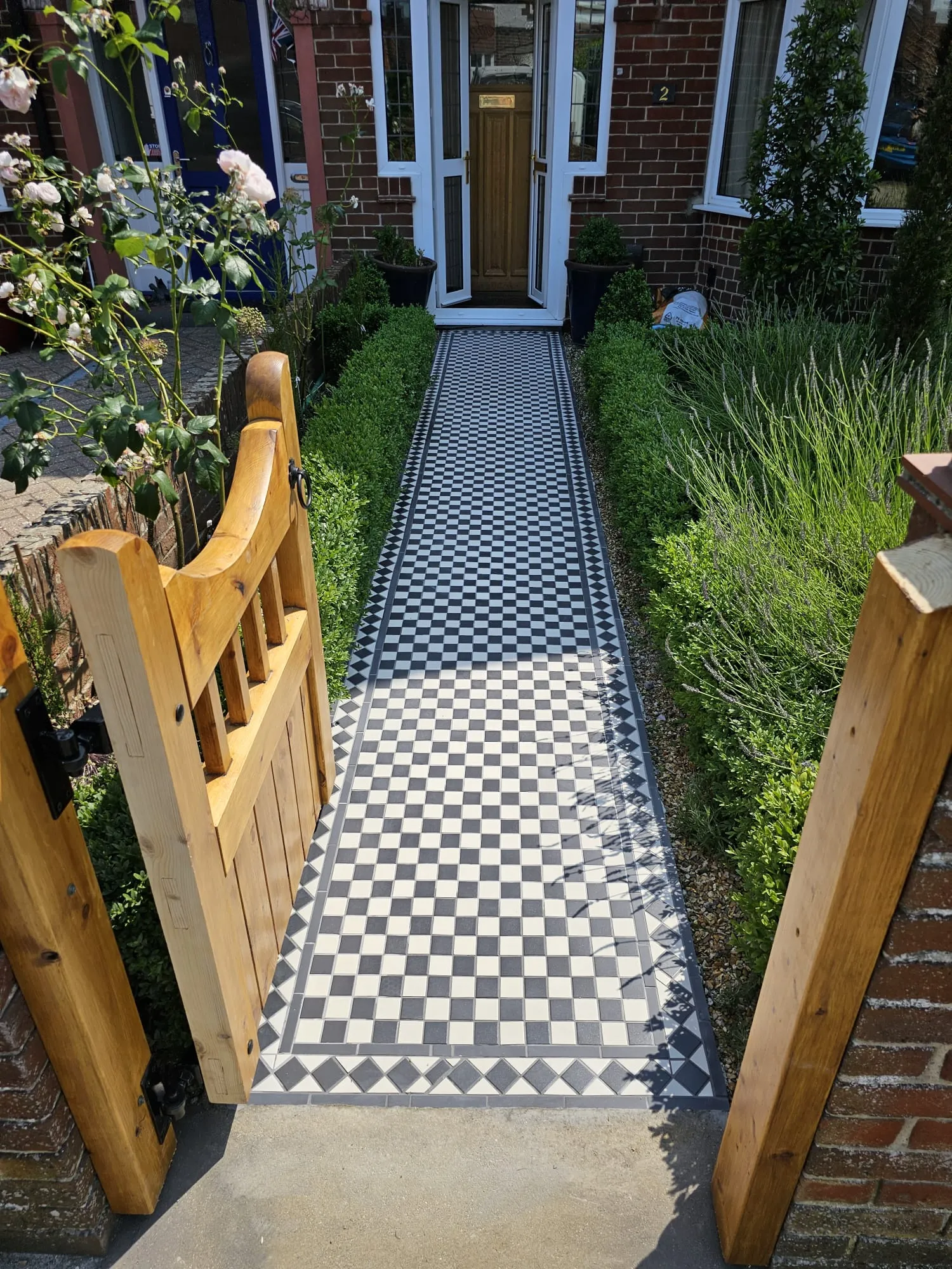 a black and white checkered tile walkway leading to a house